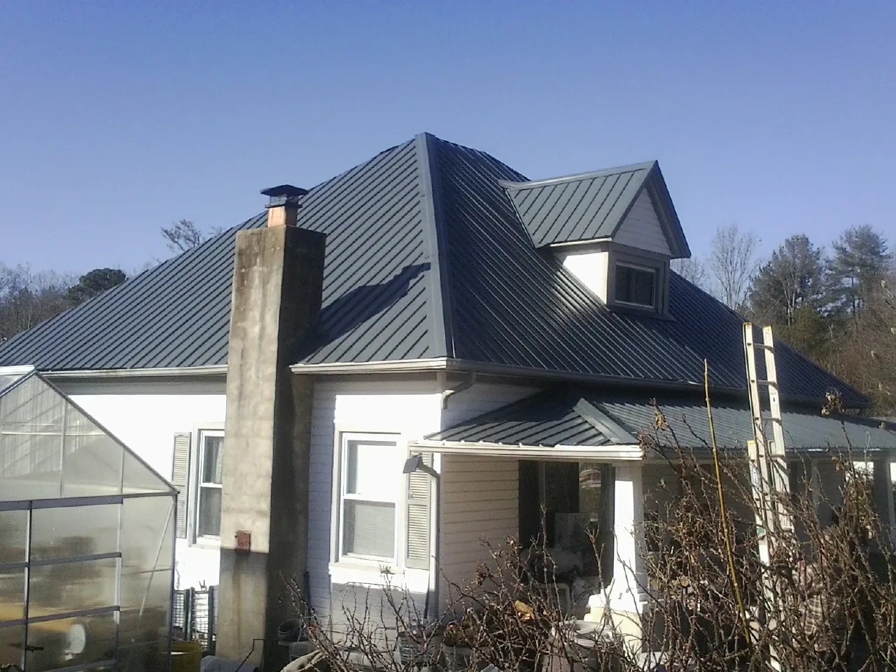 Dark blue standing seam metal roof on a white farmhouse with dormer — Slate & Tile Roof Repair by Roofing Brothers in Wickenburg