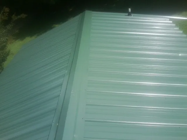New green metal panels meeting at the ridge of a roof — Flat Roof Repair work by our crew in Wickenburg