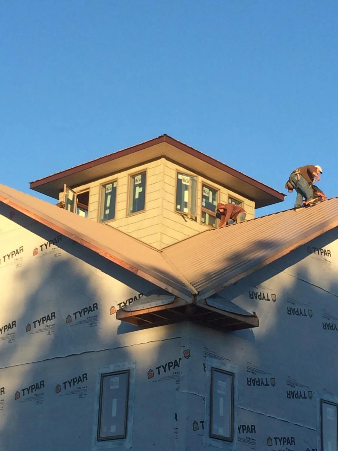 Roofers working around a rooftop cupola on a new metal roof at sunset — Roof Waterproofing in Wickenburg by Roofing Brothers